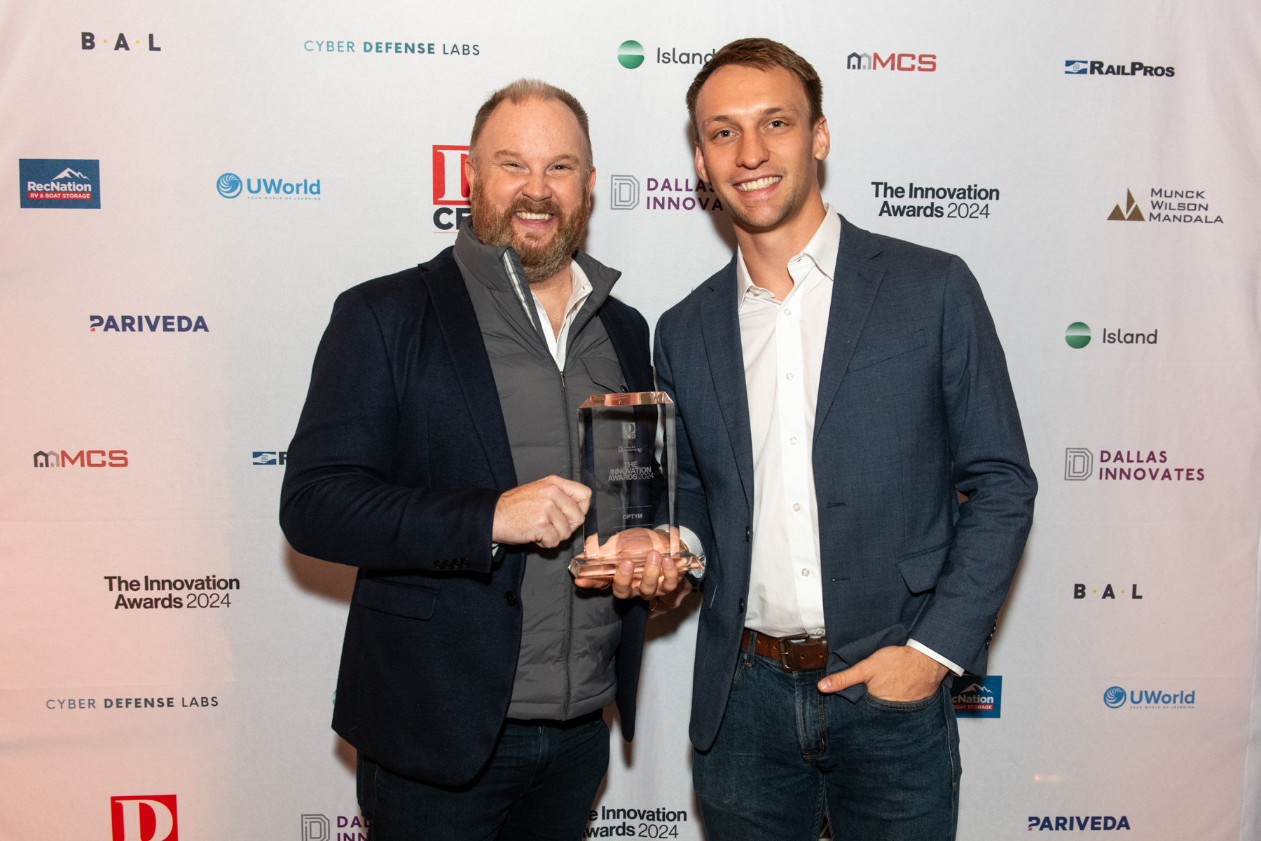 Optym Chief Strategy Officer Chris Torrence and Marketing Manager Jacob Eischen pose for a photo with the Innovation Award. 
